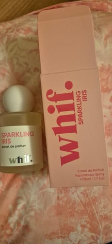 Customer's Sparkling Iris perfume bottle and its pink box displayed on a floral surface.