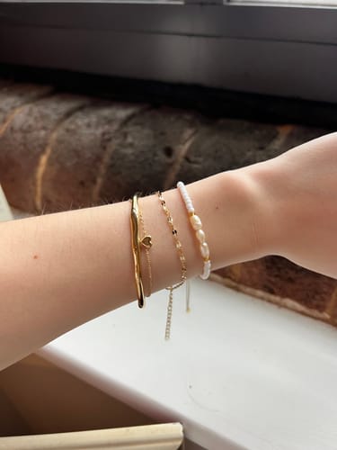 Customer wearing the gold Bamboo Bangle stacked with two other bracelets on their wrist.