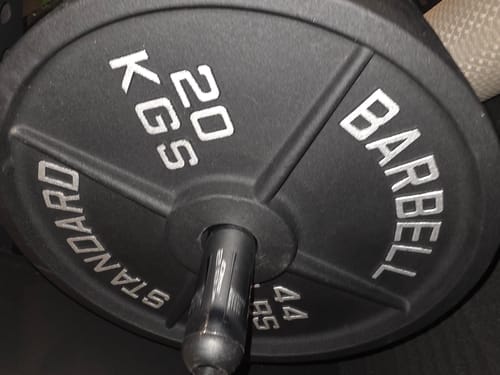 Nahaufnahme der 20-kg-Classic-Iron-Plate eines Kunden, die auf einer Langhantel steckt.