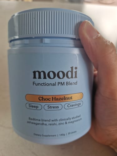 Customer holding a light blue tub of Moodi Choc Hazelnut Functional PM Blend.