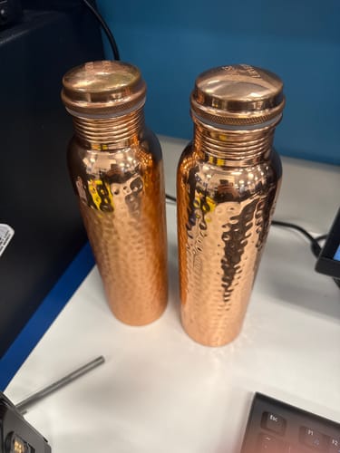 Customer's two hand-hammered Pure Copper Water Bottles standing side-by-side on a desk.