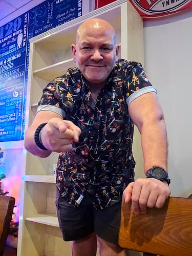 Reviewer smiling and pointing at the camera while wearing the patterned "Muppet Music Mayhem" shirt.