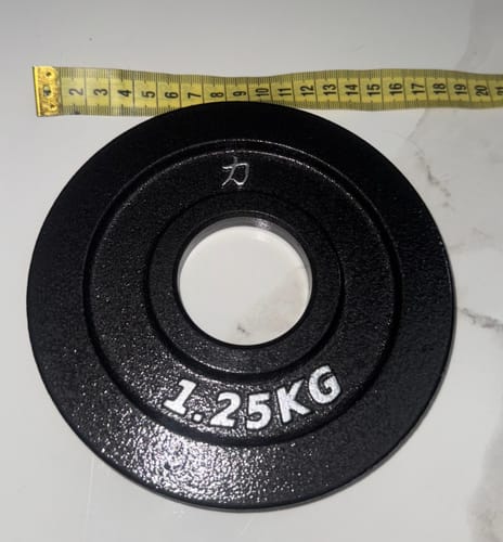 Customer's black 1.25KG Riot Cast Iron Plate with a measuring tape across the top showing its 16cm diameter.