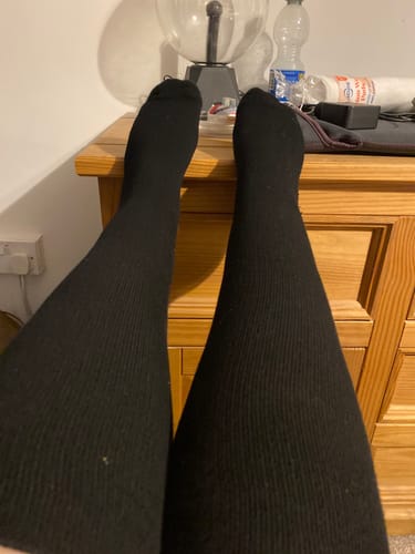 Customer wearing the black, ribbed Performance Eucalyptus Compression Socks with their feet up.