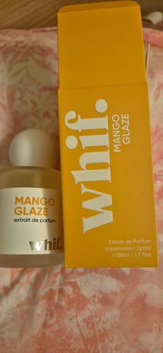 Customer's Mango Glaze perfume bottle shown next to its bright yellow product box on a patterned surface.