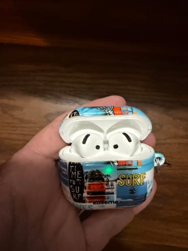 Customer's hand holds the open Aloha AirPods Case, showing the visible green charging light.