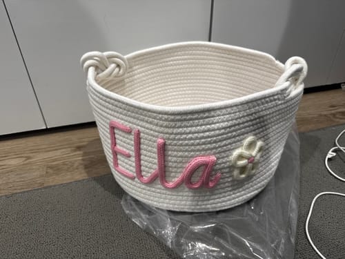 Customer's white Personalized Knitted Basket with the name 'Ella' in pink yarn and a flower icon.