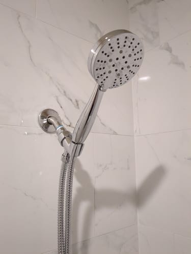 Customer's chrome 3-Spray Handheld Shower Head Set installed on a white marble tiled wall, showing its metal parts.