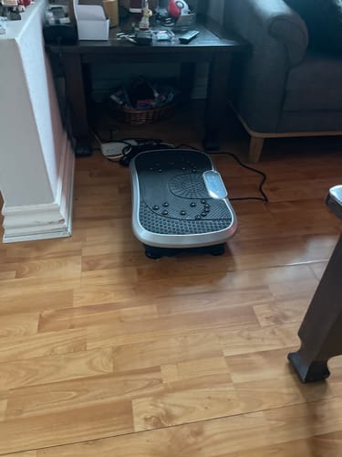 Kundes vibrationstræner placeret på et trægulv i en stue.