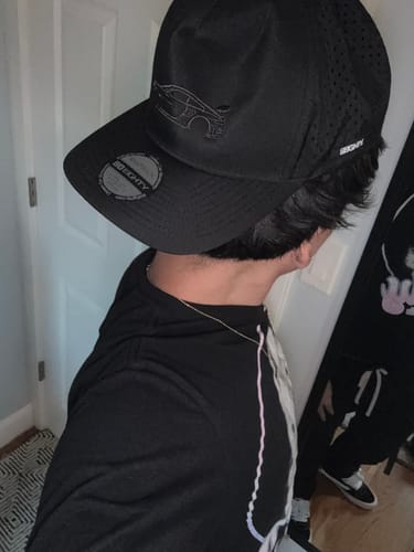 A side view of a reviewer wearing the black 80Eighty DCG#85 Hat, showing the perforated back and embroidered car logo.