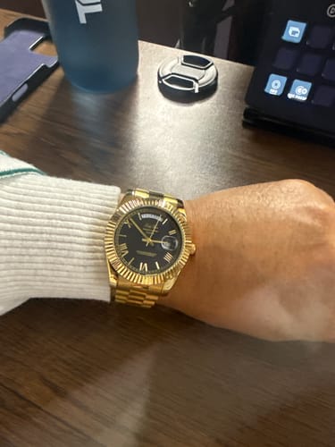 Reviewer wearing the gold Lucky Fours® Santos watch with a black dial on their wrist.