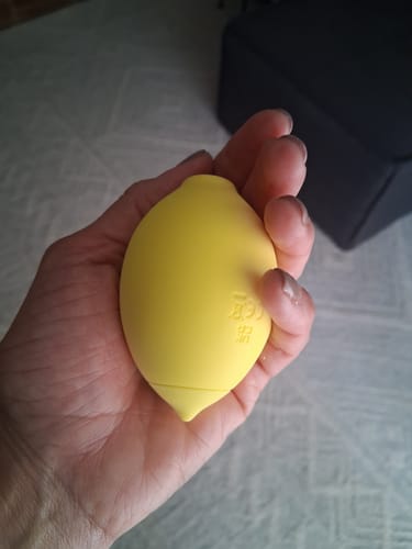 Customer holding the yellow Lem Clitoral Massager in the palm of their hand.