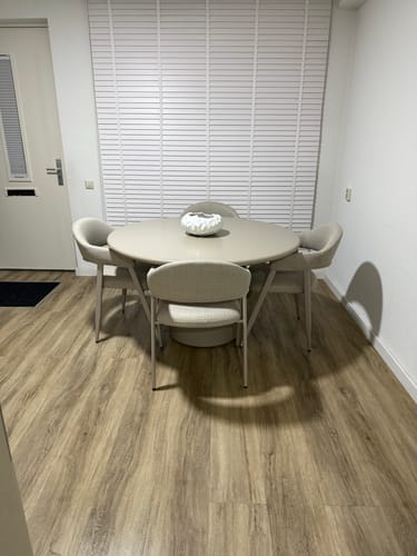 Recensent toont de beige Vasso eettafel in een lichte kamer met vier bijpassende stoelen.