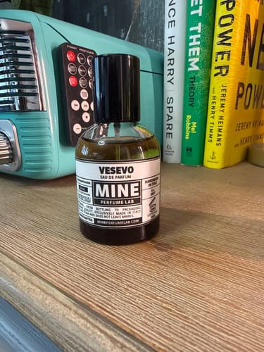 Il recensore mostra il flacone di profumo VESEVO su uno scaffale in legno.