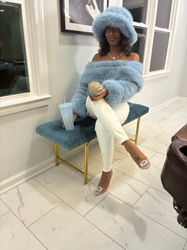 Customer sitting on a bench wearing the light blue Faux Fur Oversized Bucket Hat and matching top.