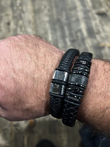 Reviewer's wrist, showing the personalized black bracelet worn alongside another black bracelet.