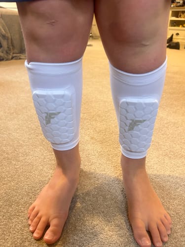 A customer wearing the white shin pads with a textured hexagonal design on their shins.