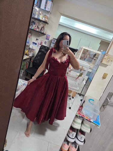 Reviewer in a mirror selfie wearing the red Cherry Hymn Midi Dress, showing its corset bodice and bow straps.