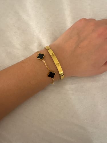Kundin trägt den goldenen Amore Armreif am Handgelenk, kombiniert mit einem weiteren Armband.