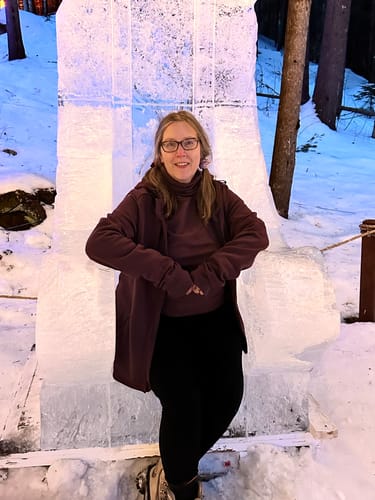 Customer sitting on an ice throne, wearing warm black Frost Duralite® Leggings in a snowy setting.