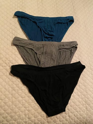 Customer's blue, gray, and black Modal Low-Rise Bikini Briefs from the 3-pack laid out on a bed.