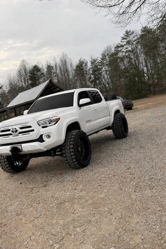 Customer's white Toyota Tacoma with a wide stance from the front after installing the 2 Inch Wheel Spacers on a gravel road.