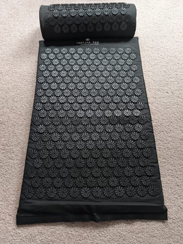 Reviewer's black Acupressure Mat Midnight and pillow set laid out on a carpeted floor.