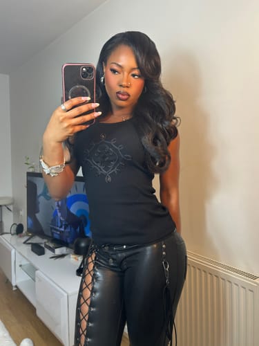 Reviewer taking a selfie in a living room wearing the black, low-rise Vice Pant with a black top.