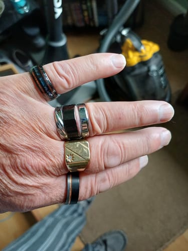 Customer's hand wearing the black Imperium ring with a sleek silver inlay and rose gold groove on the pinky finger.