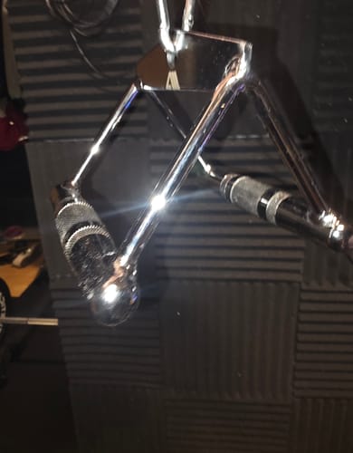 Nahaufnahme des glänzenden Parallel-Griffs eines Kunden, der an einem Fitnessgerät vor einer schallgedämmten Wand hängt.