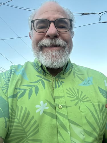Close-up of a customer smiling while wearing the bright green, patterned Zootopia 'The Wilde Side' shirt.