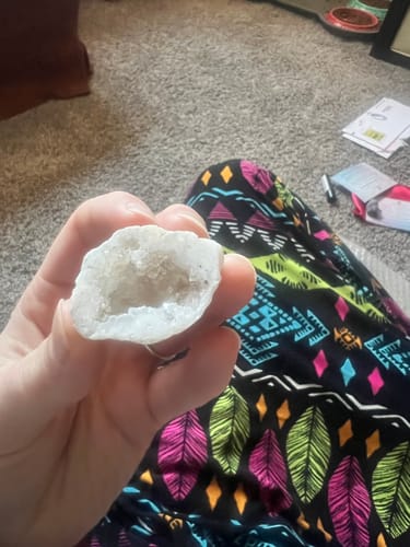 Customer holding a small white agate geode, showing the sparkling crystal-lined interior.