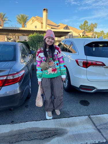Reviewer standing outdoors wearing the coffee baggy snow pants with a festive sweater.