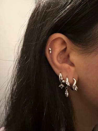 Reviewer's ear showing the silver Ripple Marquise Hoops layered with other small hoop and stud earrings.