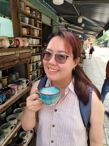 Reviewer smiling while wearing the gold Solra Necklace with a striped sleeveless top outdoors.