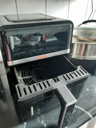 Recenzent arată friteuza Air Fryer Novio StonePro pe un blat de bucătărie, cu cuva neagră trasă afară.