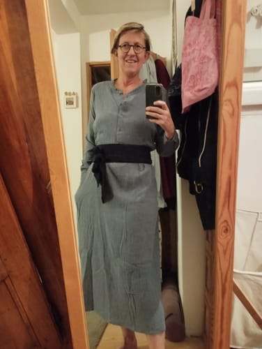 Cliente portant la Robe Aurélia bleu chiné avec une large ceinture noire nouée à la taille.