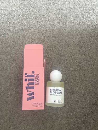 Customer's bottle of Ethereal Blossom perfume standing next to its pink box on a grey surface.