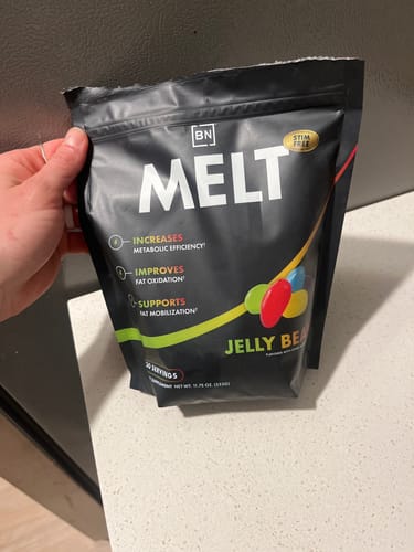 Customer holding a black pouch of the Stim-Free Melt supplement in the Jelly Bean flavor.