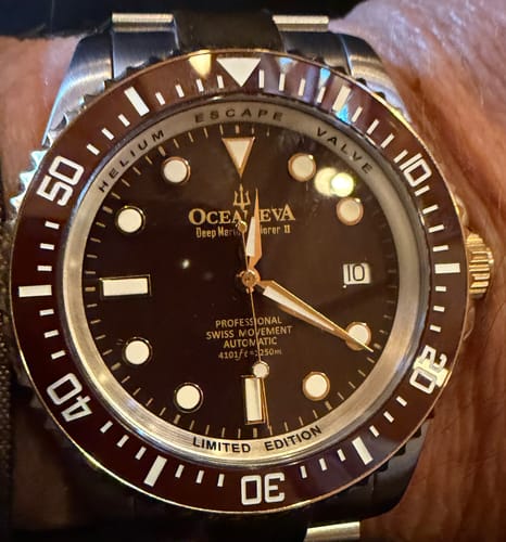 Close-up of a reviewer's Oceaneva Deep Marine Explorer II watch with a brown face and bezel, worn on a wrist.