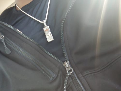 Close-up of a reviewer wearing the LOWRIDER PENDANT on a silver chain over a black shirt.