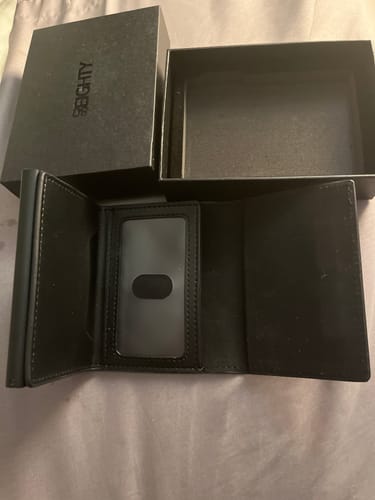 Customer's open black Onyx Wallet showing the ID window, with its packaging in the background.