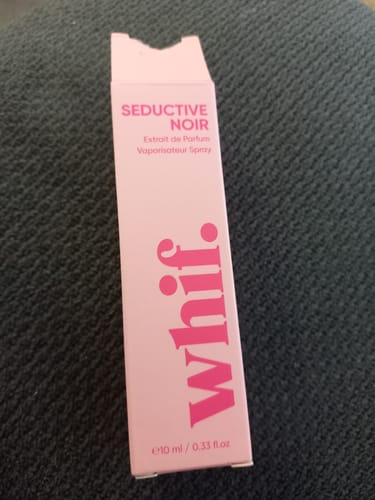 Customer's pink packaging for the Seductive Noir fragrance resting on a dark surface.