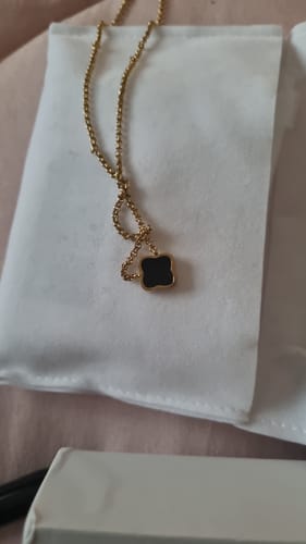 Customer's close-up of a gold-colored necklace with a black clover pendant from the December Bundle.