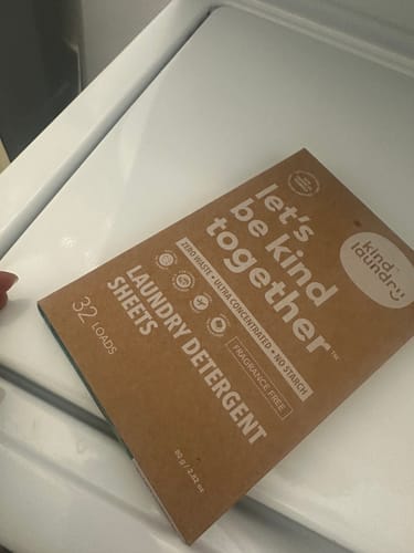 Reviewer's box of fragrance-free Laundry Detergent Sheets on a white washing machine.
