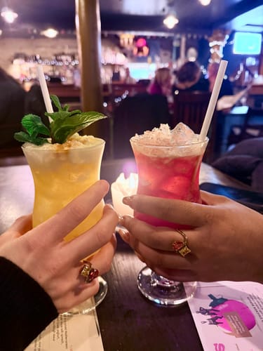 Reviewer and a friend show their matching Navae Birthstone Rings while holding cocktails at a table.