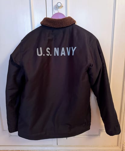 Reviewer's 1943 USN N-1 Deck Jacket hanging, showing the 'U.S. NAVY' stencil on the back and brown collar.