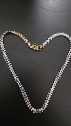 Reviewer's Reversible Arrow Link Necklace in a heart shape, showing the gold and silver sides on a dark surface.