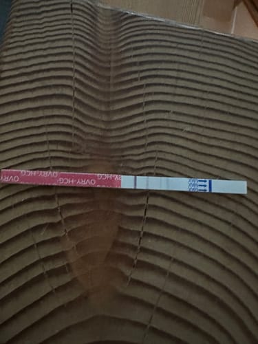 Customer's Ovry pregnancy test strip showing a positive result with two lines on a wooden surface.