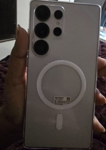 Customer holds the back of their smartphone in a clear case, protected by the UltraShield Tempered Glass.